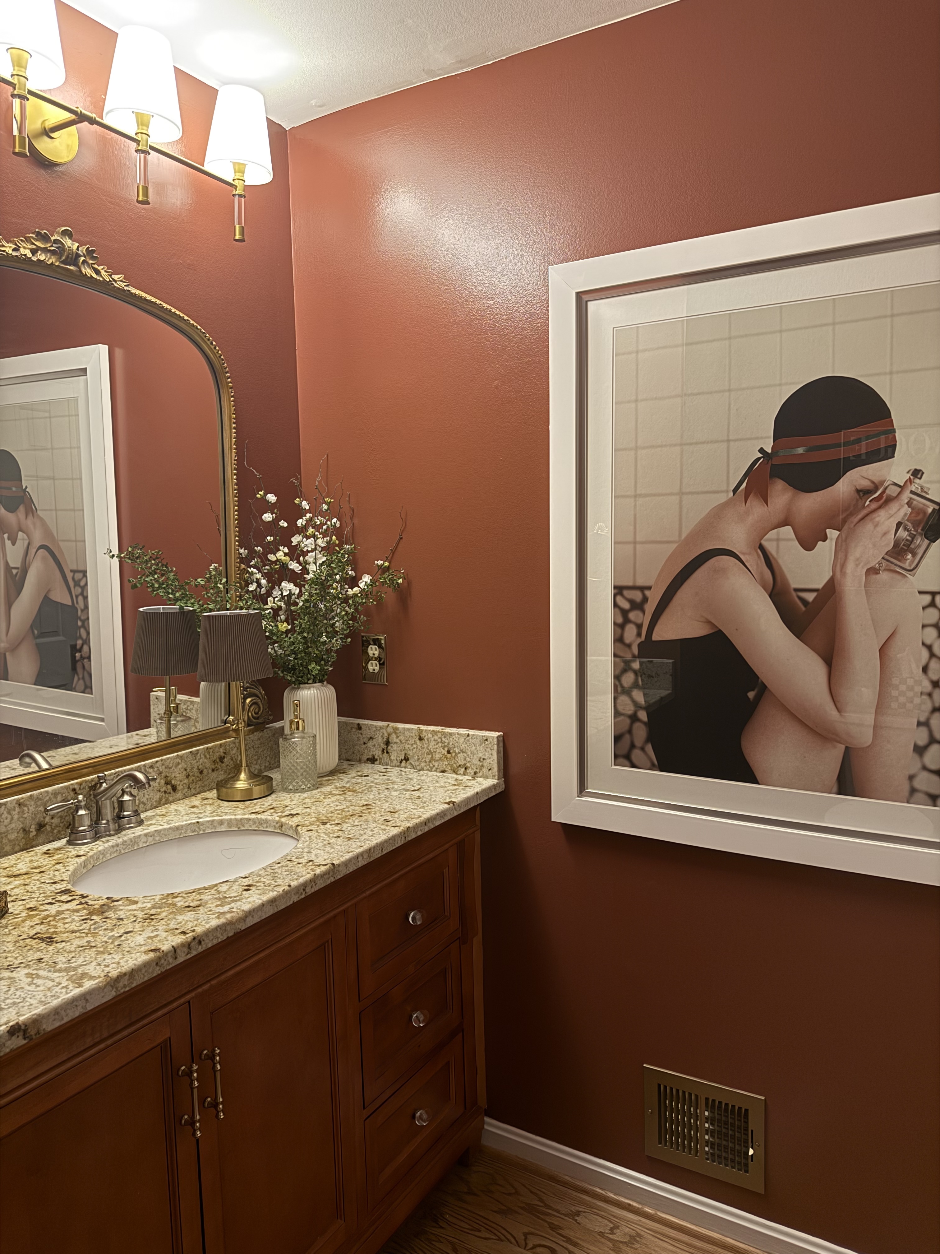 Image of a deep red powder room vanity and large portrait.